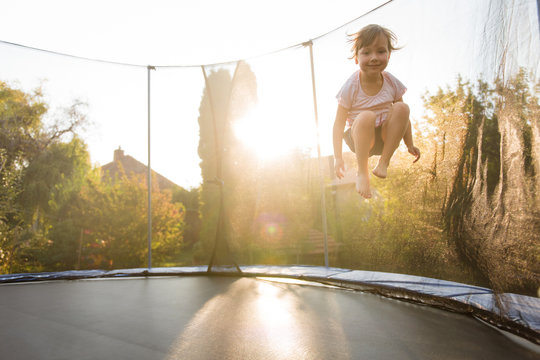 Girl child playing on trampoline in backyard