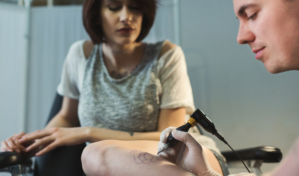 Professional tattoo artist making tattoo on leg