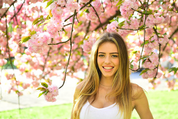 Beautiful young woman enjoying sunny day in park during cherry blossom season on a nice spring day.
