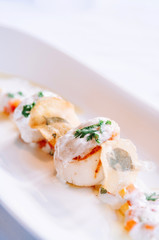 Grilled scallops on a white plate with creamy foam sauce, fine dinning cuisine