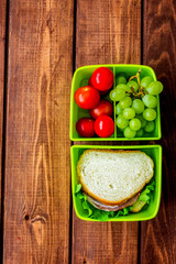 homemade lunch with cherry, grape and sandwich in green lunchbox