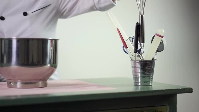 Pastry-chef putting great metalic pan on the table. Baker female taking out special kitchen devices for future tort decotation at home