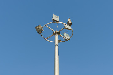concrete column with several searchlights on a blue sky background