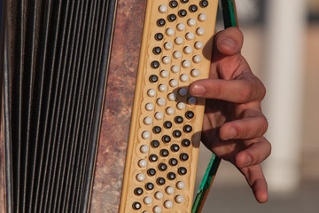 Close-up of a hand of the musician playing on keys of an old accordion