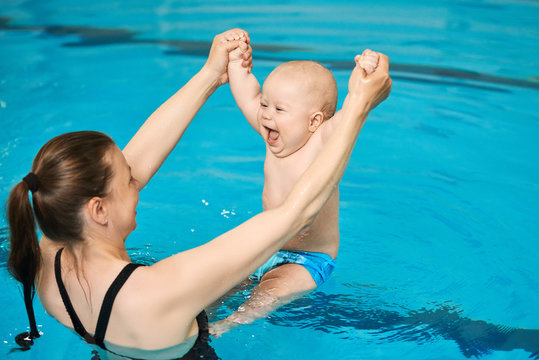 Mother teach baby to swim in water pool. Swimming lessons for children