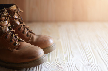 Yellow leather used work boots on wooden background closeup. Place for text