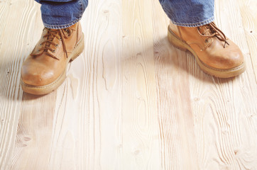 Carpenter feet in work boots standing on wooden floor. Place for text