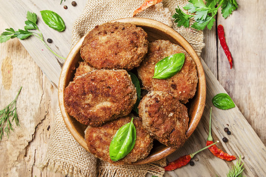 Homemade pork-beef cutlets or meatballs in a bowl, rustic style, vintage wooden background, top view