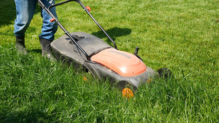 Man is mowing the grass in the garden.
