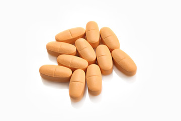 Heap of orange pills on white background