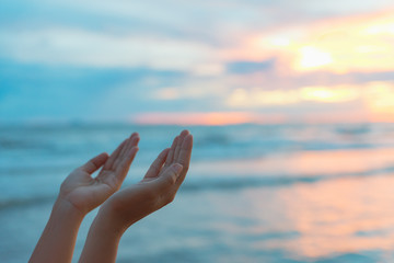 Closeup woman hands praying for blessing from god during  sunset background. Hope concept.