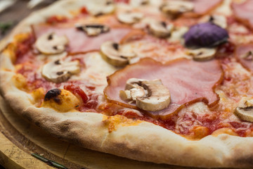 Delicious italian pizza with ham and mushrooms on wooden background