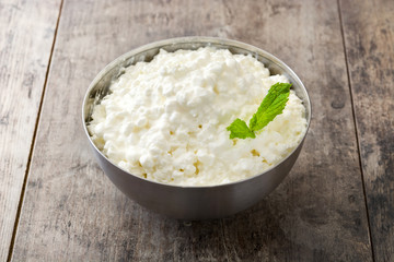 Fresh cottage cheese in a metal bowl on wooden table