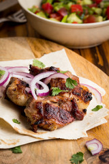 Kebab, pieces of meat, beef, pork on thin pita with onion, salad