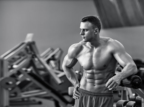 Young healthy man with perfect muscular body in the gym, black and white image
