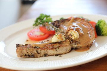 grilled pork chop with vegetable on dish with wood table background