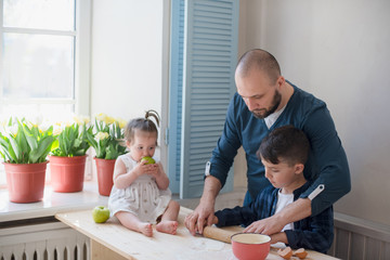 Dad with his little son and daughter baking together.