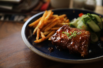 barbecued pork ribs steak with fresh vegetables on an old rustic wooden in restaurant