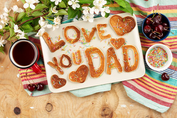 Special Father's Day breakfast. Alphabet Pancakes with sprinkles, cherries and cup of tea on wooden...