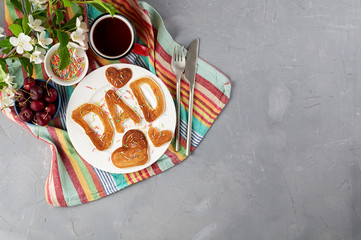 Special Father's Day breakfast. Alphabet Pancakes with sprinkles, cherries and cup of tea on a gray concrete background