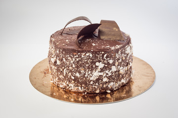 Dark chocolate vegan cake with candies and nuts on white background