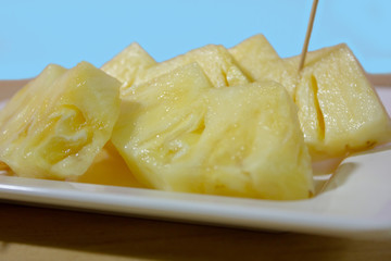 A slice of pineapple on wooden table in cyan background closeup. 