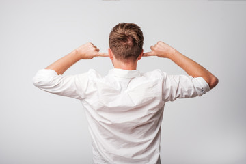 Man in whit shirt with closed ears turning back to the camera