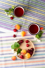 Summer still life with berry tea, ripe apricots, juicy cherries and apple blossoms