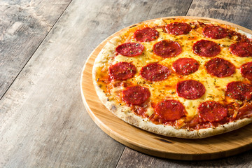 Hot italian pepperoni pizza on wooden table. Copyspace