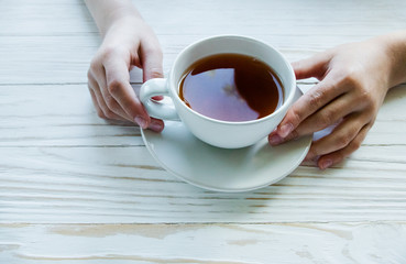 Cup of black tea on white wooden background