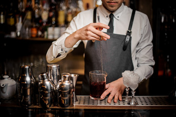 Bartender stirring a red alcoholic drink in the glass