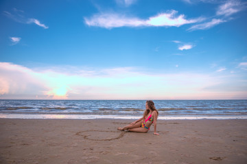 Fototapeta na wymiar Portrait happy woman sitting in the Heart shape drawing on the sand at the beach with enjoying and refreshing, summer beach relaxing time concept.