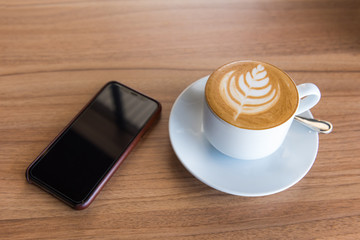 Flat white coffee with smart phone on wooden table, Top view
