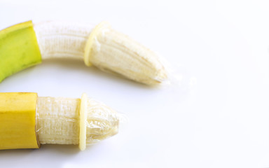 Condom onto the banana on white table background.