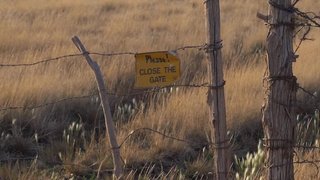 A rustic wire fence gate on a prairie ranch