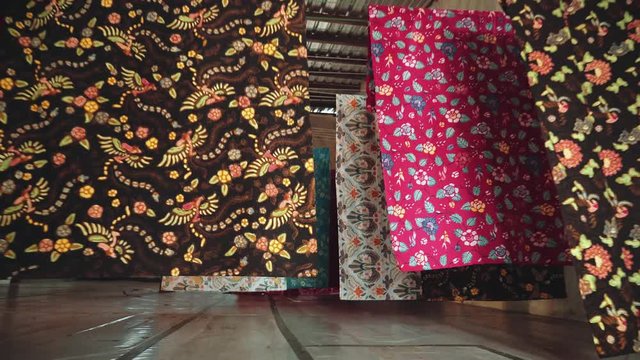 Batik fabric drying on ropes in room in factory in Java, Indonesia