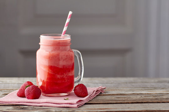 Yogurt and strawberry smoothie in jar on wooden table