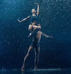 Young couple of ballet dancers dancing unde rwater drops