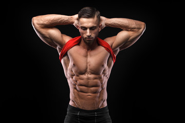 Fototapeta na wymiar Cute young sports man in red t-shirt shows relief abdominal muscles in gym