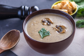 Mushroom cream soup in a brown plate on the table. Healthy autumn vegetarian traditional dish