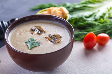 Mushroom cream soup in a brown plate on the table. Healthy autumn vegetarian traditional dish