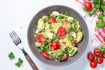 Quinoa salad with spinach, avocado and tomatoes top view.