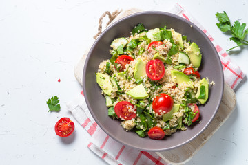 Quinoa salad with spinach, avocado and tomatoes top view.