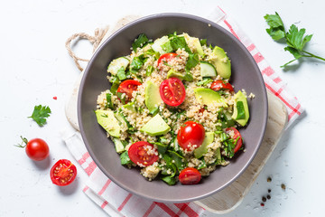 Quinoa salad with spinach, avocado and tomatoes top view.
