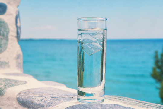 Glass of water with ice on the beach 