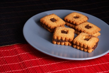 Stacked chocolate chip cookies on gray style plate on red and black wooden table