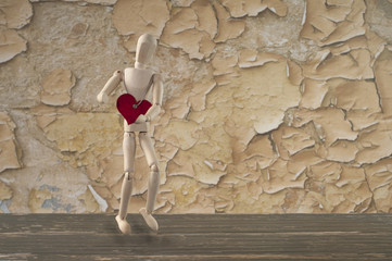 drewniany manekin z czerwonym sercem na tle starej ściany © iwona666