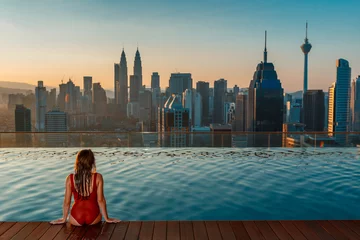 Fotobehang Asian travel and vacation. Young woman enjoying the city view from roof top swimming pool. © Sokirlov