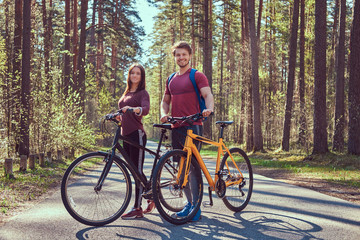 Fototapeta premium Group of young friends hiking through the forest with bikes on a beautiful summer day