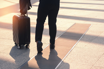backside of beautiful traveler girl holding and pull luggage walking on concrete floor at outdoor in the city with sunlight and go to travel planing in vacation time concept.